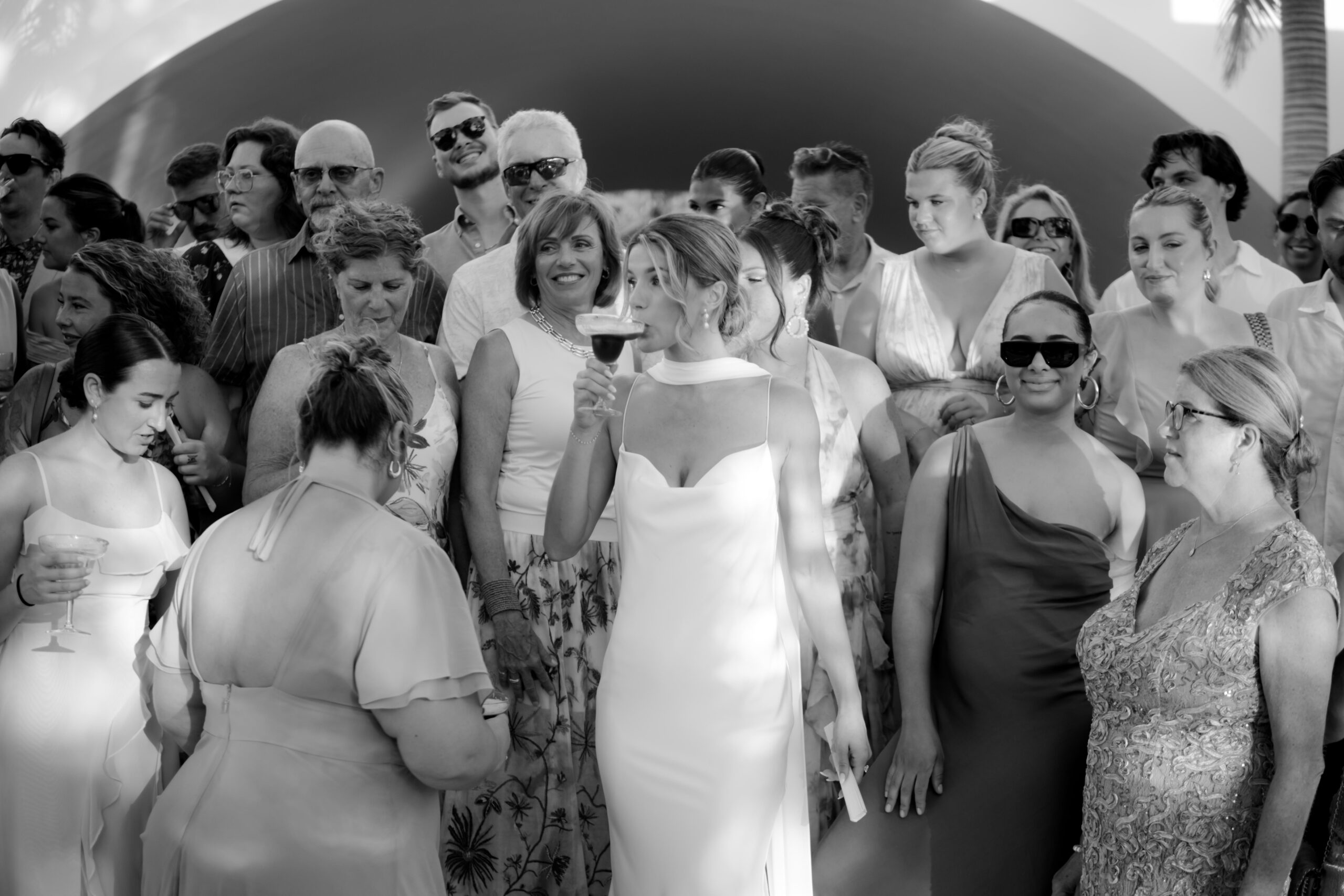 Bride drinking a cocktail surrounded by wedding guests during a destination wedding celebration in Tulum