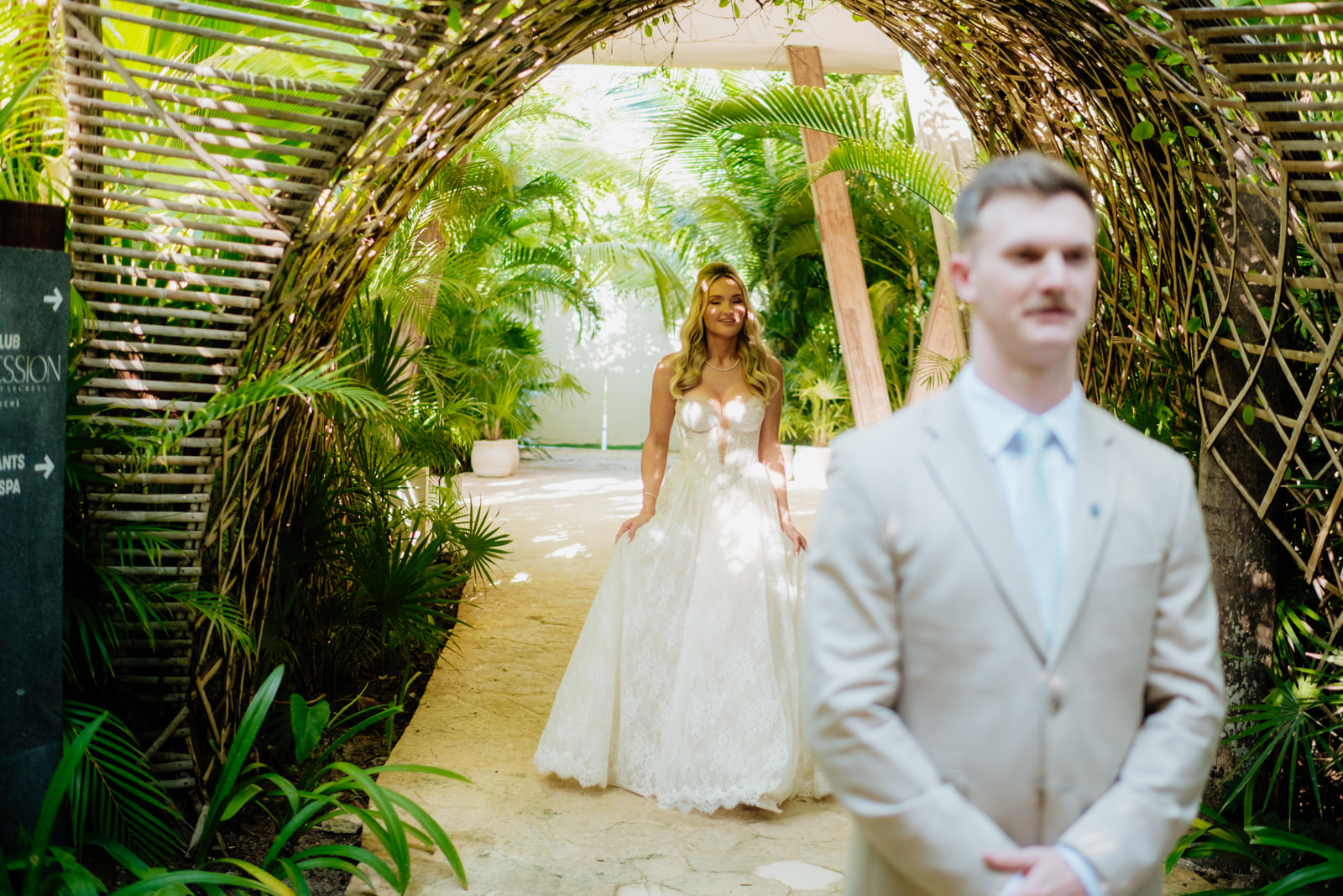 Bride walking toward the groom during a destination wedding first look in a tropical garden in Tulum Mexico